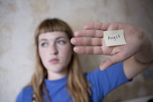Student holding a hand in front of her eyes, a note with the word fear on her hand model released Symbolfoto property released  FLLF00184