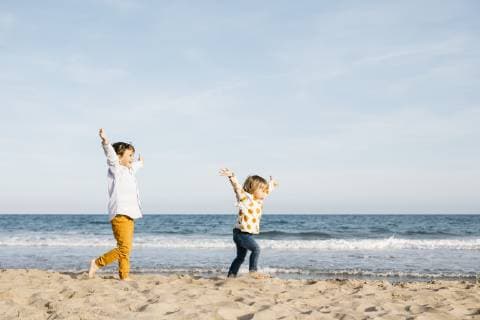 Happy boy and his little sister running together on the beach model released Symbolfoto  JRFF03229