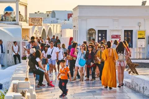 Tourists in restaurants and on Oia Castle wait for the sunset with Caldera View and the famous Windmill in Oia, Santorini , Greece at 04 June 2019. Photographer: Peter Schatz