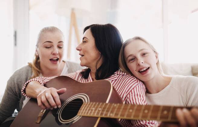 IMAGO Creative: Digitale Welt, Verzicht auf Technologie Mature woman with two daughters singing and playing guitar at home model released Symbolfoto property released  HAPF02963