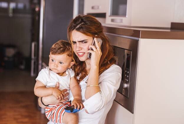 Annoyed mother with her son talking on the phone at home model released Symbolfoto property released  LJF00266