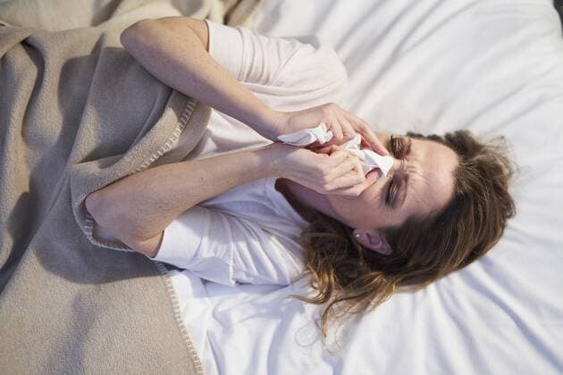 Woman lying in bed blowing her nose model released Symbolfoto  PNEF01660