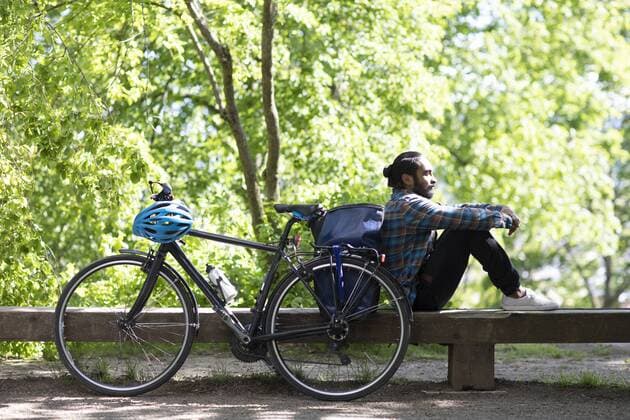 Young man with bicycle relaxing on a bench model released Symbolfoto  SGF02375