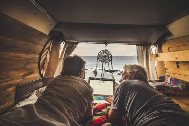 Senior couple traveling in a vintage van, using laptop model released Symbolfoto  SIPF01984