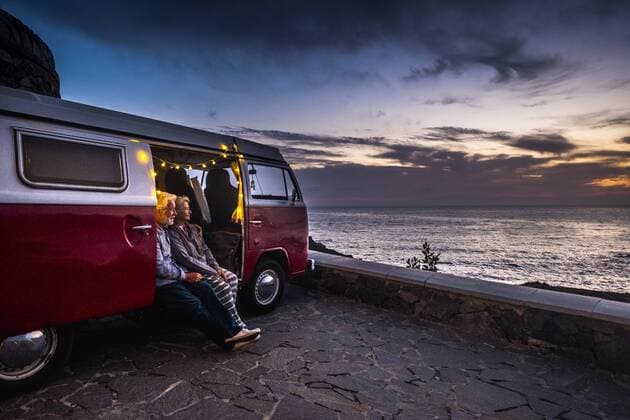 Senior couple traveling in a vintage van, watching sunset at the sea model released Symbolfoto  SIPF01988