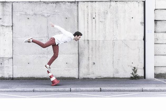 Young man balancing on traffic cone in front of concrete wall model released Symbolfoto  UUF17829
