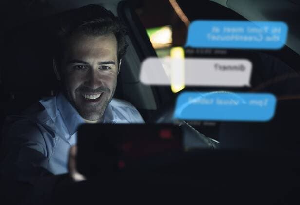 Smiling businessman using cell phone for messaging i in car at night model released Symbolfoto property released  UUF17923