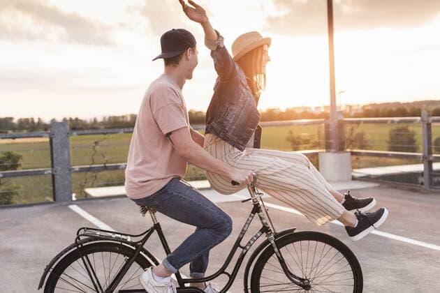 Happy young couple together on a bicycle on parking deck at sunset model released Symbolfoto  UUF17972