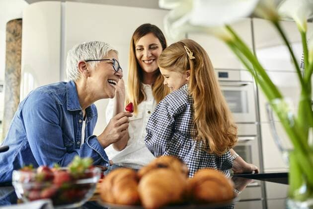 Grandmother offering stawberry to granddaughter, mother watching model released Symbolfoto property released  ZEDF02323