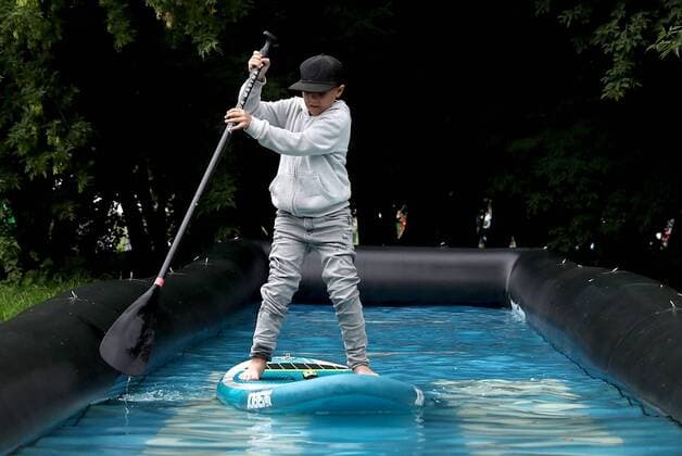 MOSCOW, RUSSIA - AUGUST 3, 2019: A boy standup paddleboarding at the 2019 Afisha Picnic music festival at Moscow s Kolomenskoye Museum-Reserve. Anton Novoderezhkin TASS  TS0B5551