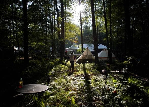 A man walks in the woods through the camp site at the Yasgur Road Reunion celebrating the 50th anniversary of the Woodstock Music Festival at Yasgur Farm on Friday, August 16, 2019 in Bethel, New York. Woodstock was a music festival held August 15Ð18, 1969, which attracted an audience of more than 400,000 and is widely regarded as a pivotal moment in popular music history.  NYP20190816157 JOHNxANGELILLO