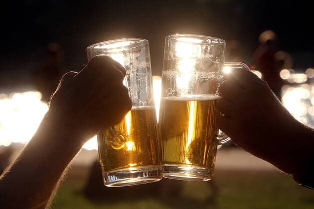 Gemeinsames Zuprosten mit Biergläsern bei untergehender Sonne im Gegenlicht in Frankfurt, Hessen, Deutschland
