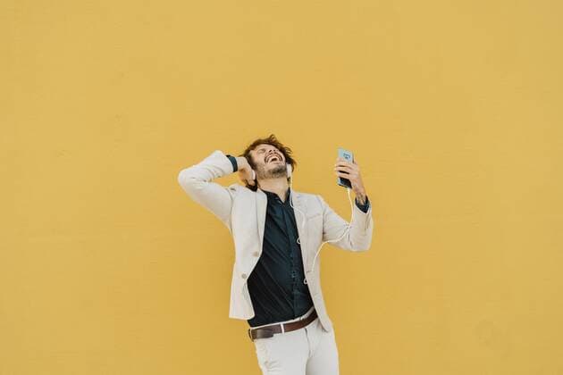 Tag der Musik am 21. Juni Businessman singing and dancing in front of yellow wall listening music with headphones and smartphone model released Symbolfoto  AFVF03422