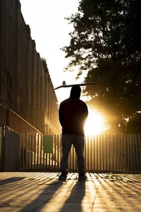 Back view of skater standing at backlight with skateboard on his head model released Symbolfoto  AFVF03563