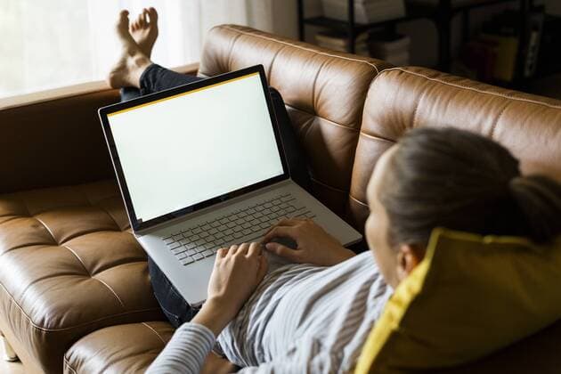 Young woman lying on couch at home using laptop model released Symbolfoto property released  GIOF06722