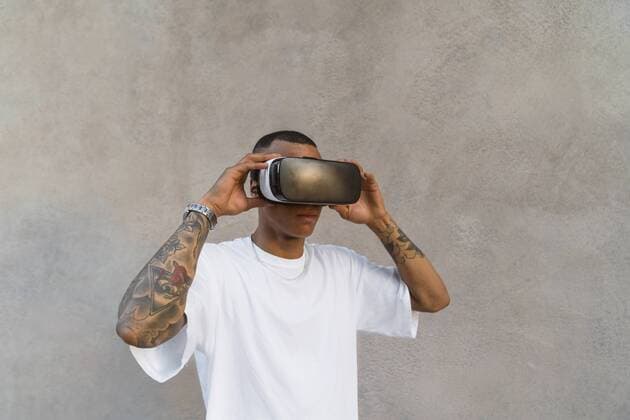 IMAGO Creative: Neue Aussichten Tattooed young man using Virtual Reality Glasses looking up model released Symbolfoto  MGIF00582