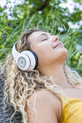 Smiling woman listening to music with closed eyes, lying on deckchair model released Symbolfoto property released  TCF06179