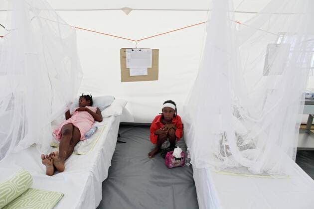 Carrefour, Haiti - Erdbeben-Naturkatastrophe. Deutsche Rote Kreuz Feld-Krankenhaus, Carrefour 30.01.2010, Carrefour, Quest, Haiti, HTI - Erdbeben Haiti. Deutsche Rote Kreuz Field Hospital. Junge Mutter hockt neben ihrem, im Bett liegenden, durch ein Moskitonetz geschuetztem Kleinkind. Carrefour Quest Haiti *** Carrefour, Haiti Earthquake Natural catastrophe German Red Cross Field Hospital, Carrefour 30 01 2010, Carrefour, Quest, Haiti, HTI Earthquake Haiti German Red Cross Field Hospital Young mother squats next to her toddler lying in bed and protected by a mosquito net Carrefour Quest Haiti