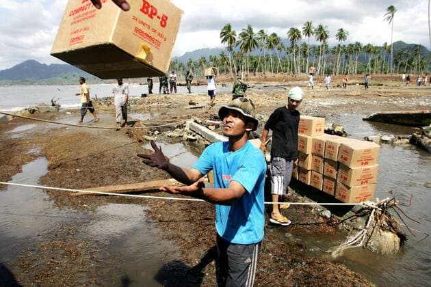 Lhok Nga, Indonesien - Care Hilfsguetertransport fuer Tsunami-Opfer 12.01.2005, Lhok Nga, Sumatra, Indonesien, IDN - Mitarbeiter der Hilfsorganisation Care International beim Entladen eines Schiffes mit Hilfsguetern fuer Tsunami-Opfer, an der Kueste von Lhok Nga. Lhok Nga Lhok Nga Indonesien *** Lhok Nga, Indonesia Care Relief transport for tsunami victims 12 01 2005, Lhok Nga, Sumatra, Indonesia, IDN staff of the relief organization Care International unloading a ship with relief supplies for tsunami victims, at the coast of Lhok Nga Lhok Nga Lhok Nga Indonesia
