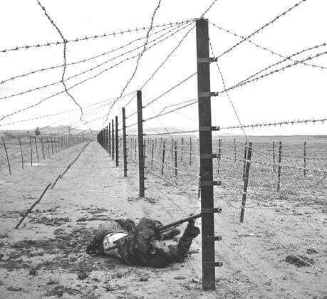 War in Algeria, Rebel electrocuted in the barbed wire (1957) Algerian War of Independence Rebel carrying a gun, electrocuted in the barbed wire at the Tunisian-Algerian border. 1957 Copyright: xPhoto12 Photosvintagesx WTZ04197_002