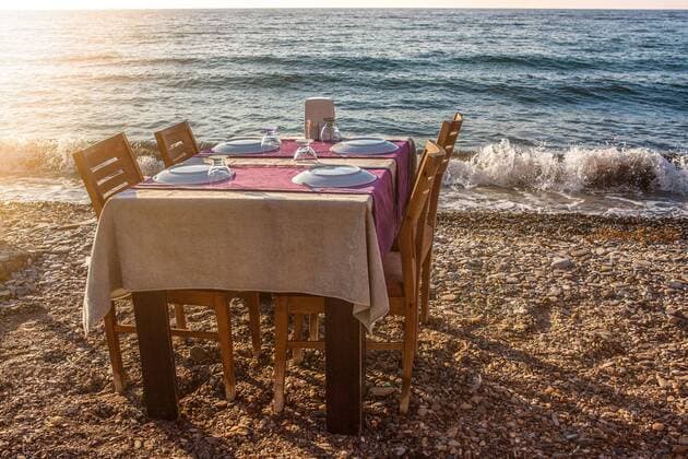 gedeckter Tisch für vier Personen mit Stühlen eines Restaurants im Freien am Ufer des Meeres in einem Ferienort in der Türkei Kusadasi, Türkei