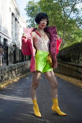 Street Style on day three of London Fashion Week SS 2020 on Saturday September 14th 2019, showcasing stylish individuals London is internationally known for. Image shows Chinese PR and nfouencer Harper Silin. She wears a white lace top by House of CB, yellow bots by Zara, lime green knitwear shorts by Jojo Ruiji Zhou, a mini bag by GB David and a large pink jacket  (112123982)