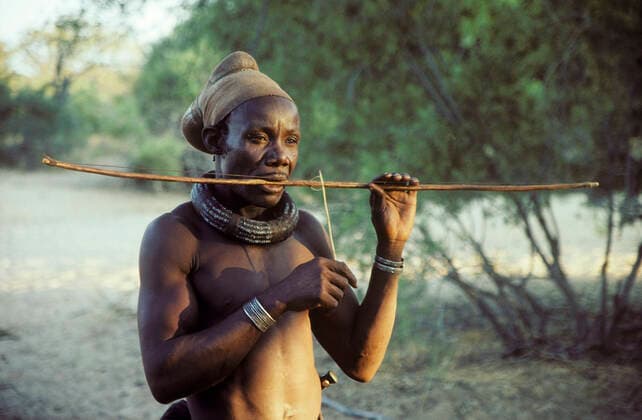 IMAGO Cultures of the world, Himba Volk in Namibia Himba man playing a stringed instrument - the head scarf indicates the married man - Kaokoveld - Namibia  Copyright: ThomasxDressler 10761805