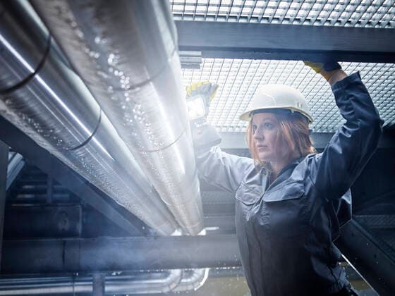 Craftswoman wearing hard hat working at pipe model released Symbolfoto property released  CVF01465