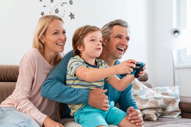 Happy parents with son playing video game on couch at home model released Symbolfoto property released  DIGF08192