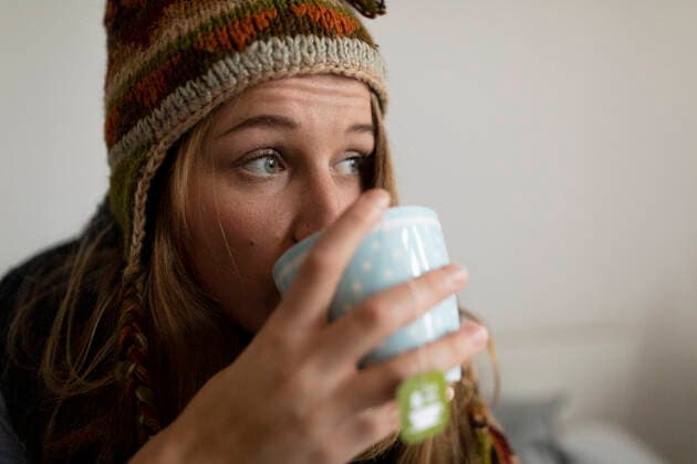 Ill young woman drinking tea in bed at home model released Symbolfoto property released  GUSF02519