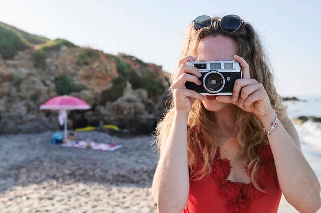 Young woman taking a picture on the beach model released Symbolfoto  IGGF01318