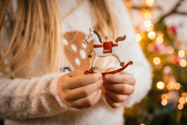 Decorating the christmas tree, girl holding an ornamental metal rocking horse model released Symbolfoto  IPF00524