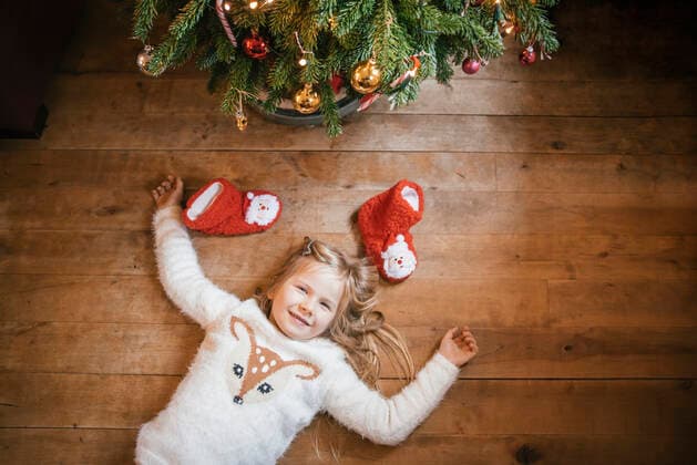Smiling girl lying under the Christmas tree model released Symbolfoto  IPF00528
