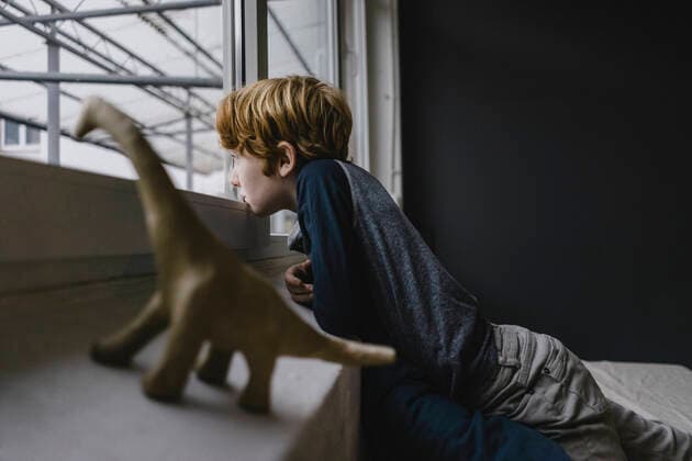 Sad boy leaning on window sill looking out of window in the evening model released Symbolfoto property released  KNSF06287
