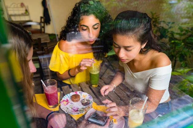 Creative Highlights Symbolfotos Three young women with smoothies meeting in a cafe sharing smartphone model released Symbolfoto property released  MGIF00688
