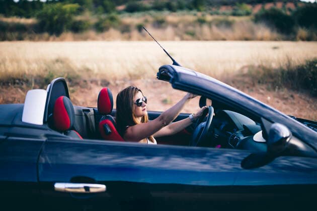 Young woman wearing sunglasses, sitting in her convertible model released Symbolfoto  OCMF00604