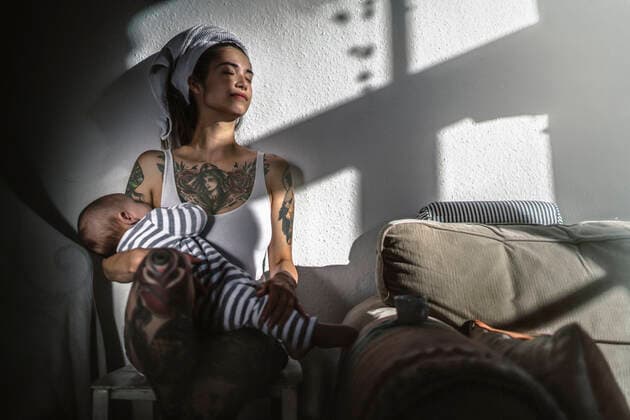 Tattooed young woman holding her baby at home enjoying the sunshine model released Symbolfoto property released  RIBF01016