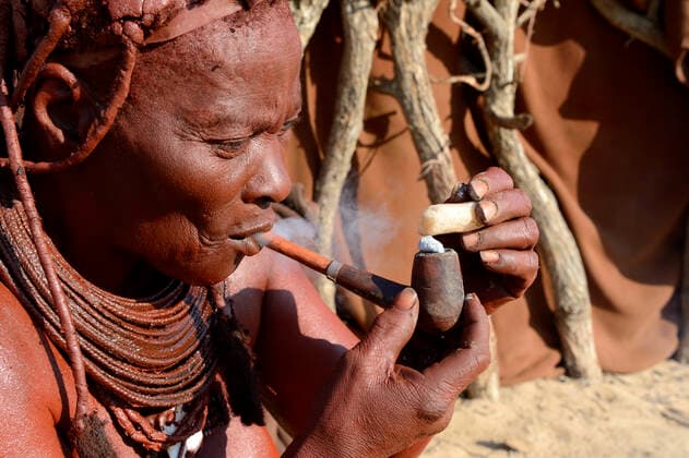 IMAGO Cultures of the world, Himba Volk in Namibia Himba woman lighting and smoking her pipe, Marienfluss Valley, Kaokoland Desert, Namibia. October 2015  1531094 EricxBaccega
