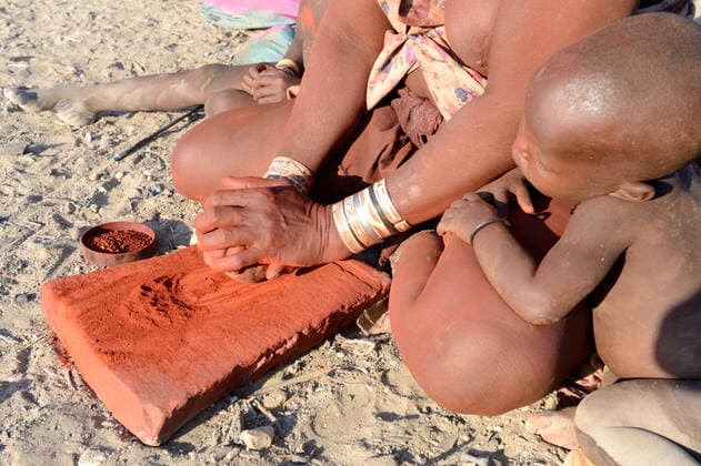 IMAGO Cultures of the world, Himba Volk in Namibia Himba woman crushing ochre into powder, Marienfluss Valley. Kaokoland, Namibia October 2015  1531131 EricxBaccega