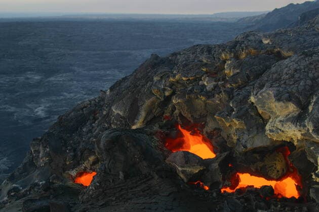 Skylights in the roof of a lava tube reveal the red hot liquid lava travelling through the tube toward the ocean from Kilauea Volcano, Hawaii Volcanoes National Park, Ka u, Hawaii, USA, March 2003  1555735 DougxPerrine
