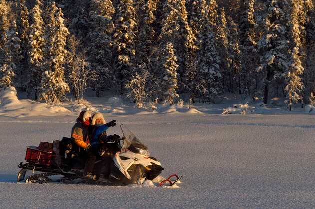 Nils-Torbjorn Nutti, owner and operator at Nutti Sami Siida, and Klara Enbom-Burreau on snowmobile trip into the wilderness, Jukkasjarvi, Lapland, Laponia, Norrbotten county, Sweden Model released.  1559006 StaffanxWidstrand