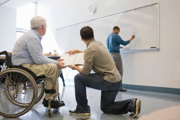 University professor with Muscular Dystrophy teaching his students in a classroom  Copyright: MarkxHunt 12559164, model released, property released