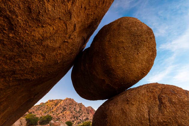 Granite Boulders in canyon, Little Dragoon Mountains in background in sunset light, Texas, USA, August.  1563015 JackxDykinga