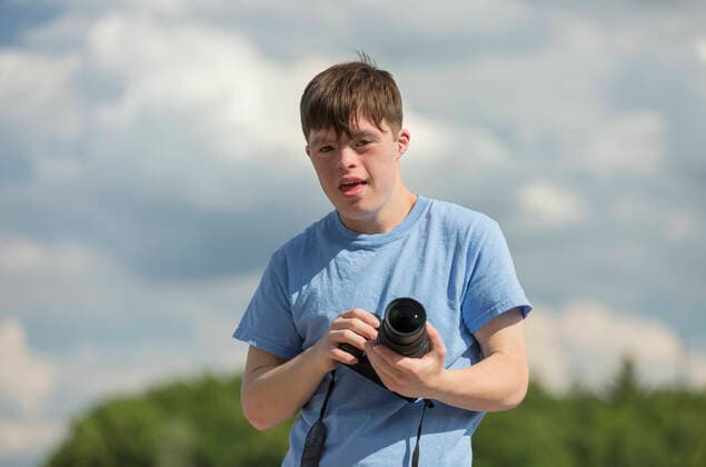 Young man with Down Syndrome holding a camera  Copyright: MarkxHunt 12563614, model released, property released