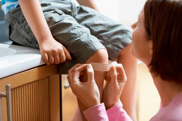 Mother Applying Bandage to Son s Knee,model released, Symbolfoto,property released 03B65974