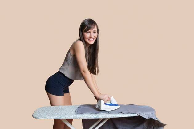 IMAGO Creative: Haushaltsgeräte, Bügeleisen Portrait of a young woman ironing shirt over colored background,model released, Symbolfoto 03B91222
