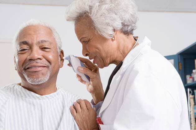 Senior medical practitioner takes patient s temperature,model released, Symbolfoto,property released 03C03014