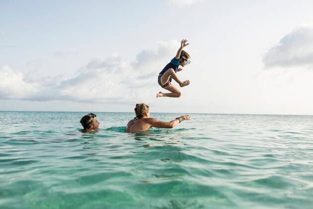 IMAGO Creative, Jahreszeit Sommer, Sommerferien 5 year old son on mother s shoulders leaping into the ocean at sunset 5 year old son on mother s shoulders leaping into the ocean at sunset  58769