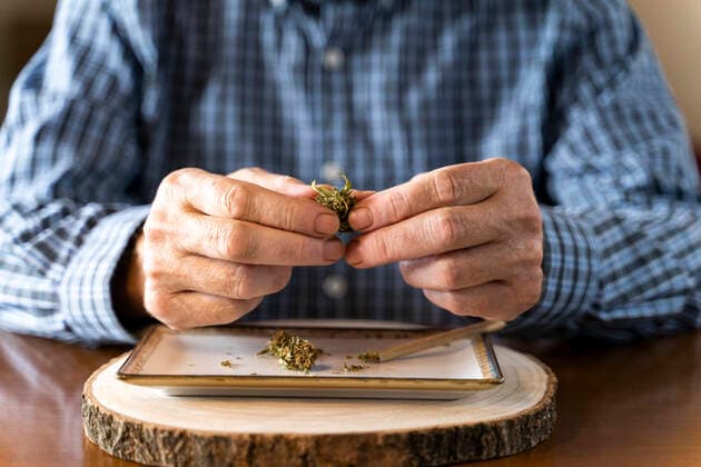 Senior man at home rolling marihuana joint model released Symbolfoto property released  AFVF04122