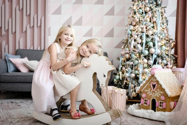 Portrait of happy two little girls together on a rocking horse at Christmas time model released Symbolfoto property released  EYAF00565